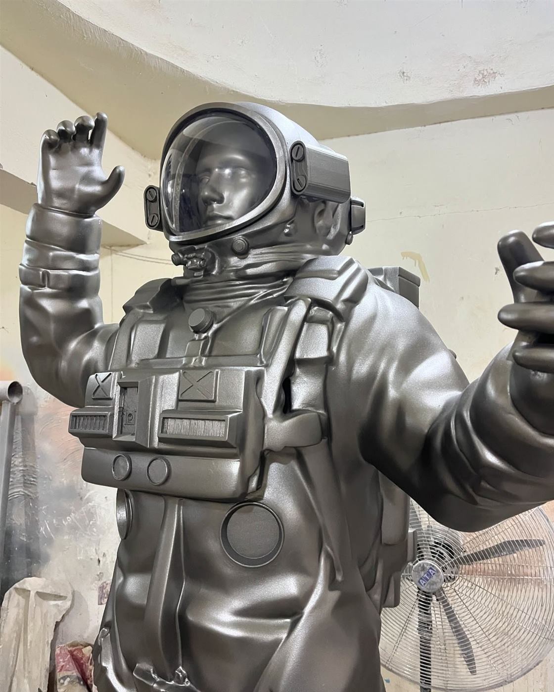 Life size metallic astronaut sculpture with raised hand