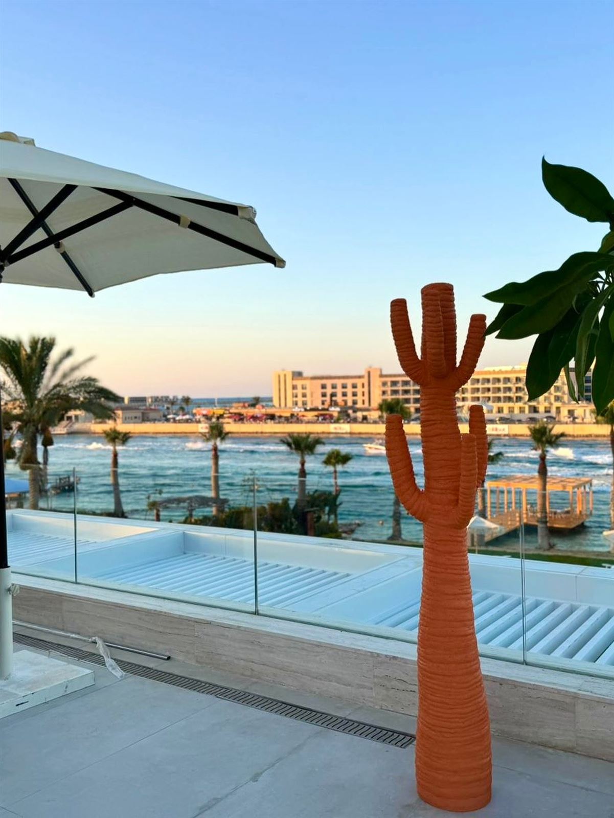 Sculpted cacti in white and terracotta on a villa terrace overlooking the sea