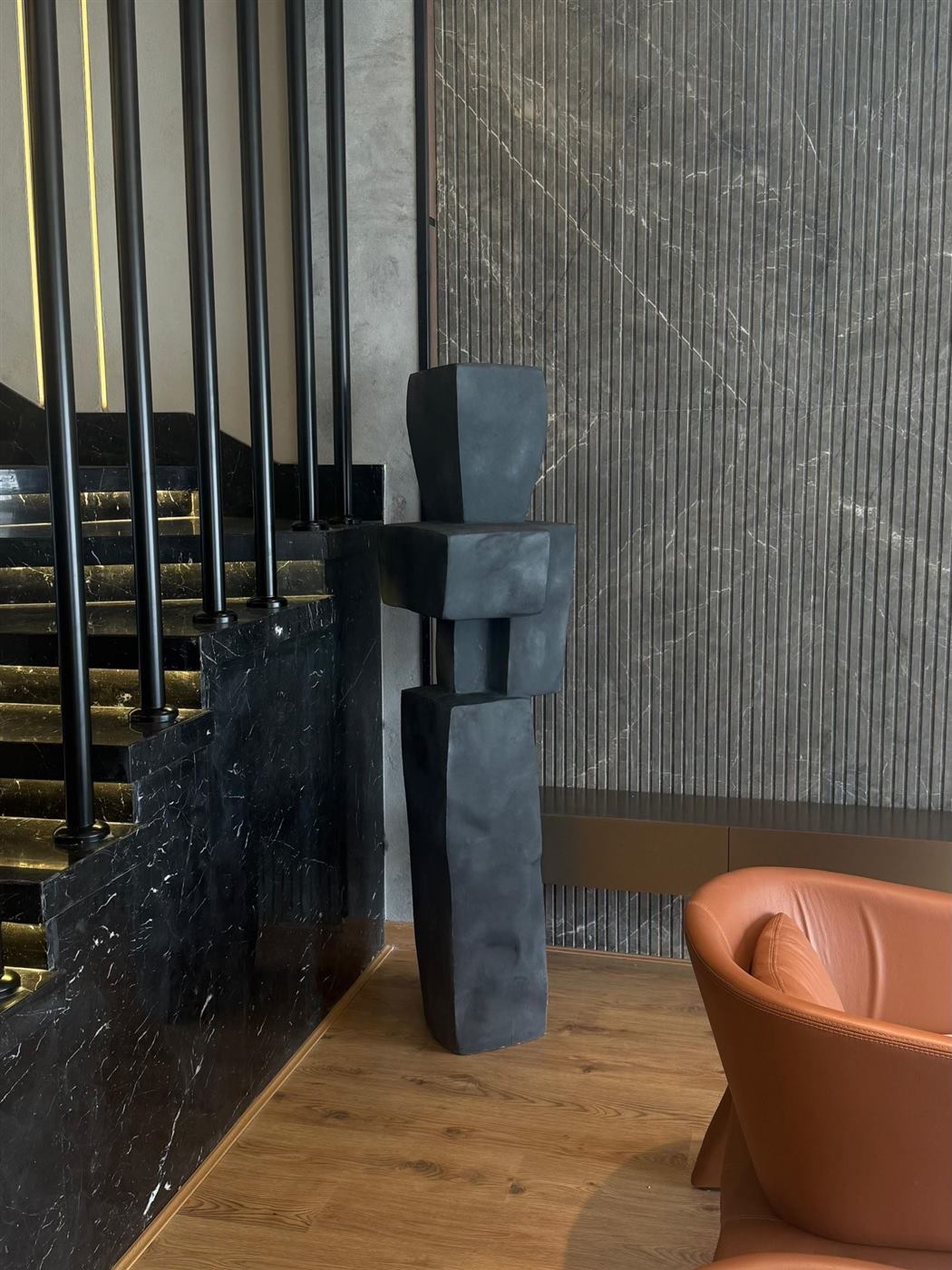 Two cubist stone figures standing by a dark marble staircase