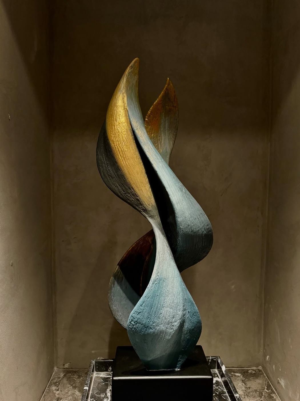 Twisting flame form in bronze and teal patina on a marble base