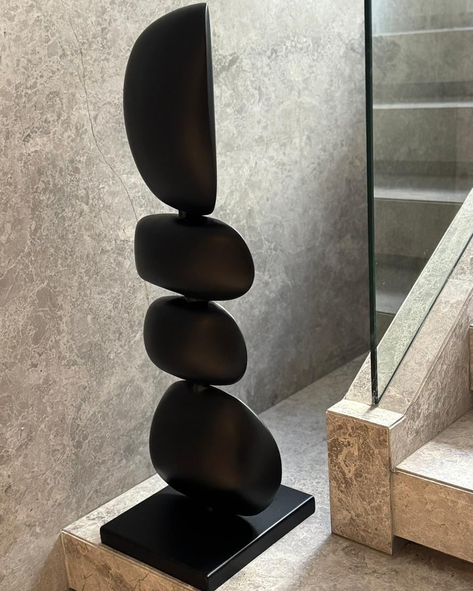 Stacked black pebble totem beside a marble staircase